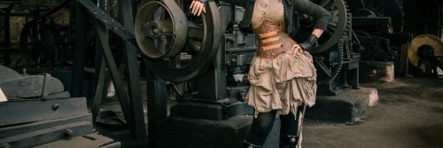 Kobieta w stroju w stylu cosplay stoi przy maszynach XIX-wiecznego zakładu w Maleńcu.